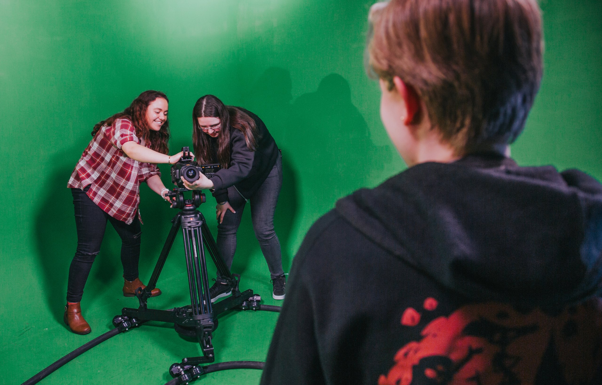 A close-up of students filming on a camera in a film studio.