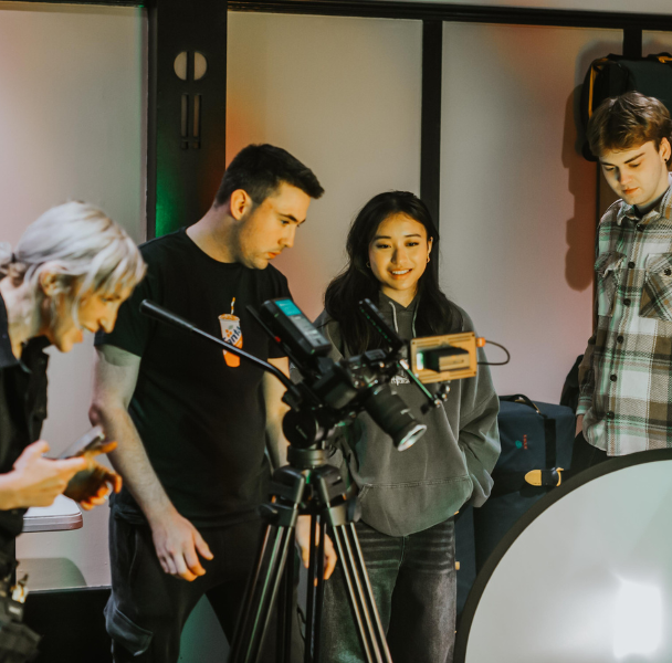 A group of students operating a camera and filming in a studio.