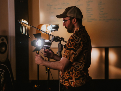A close-up of a tutor operating lighting in a dim film studio.