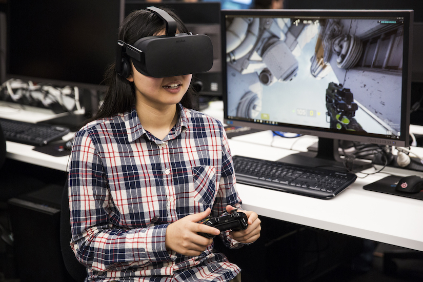 A close-up of a student wearing VR goggles and playing a game in virtual reality.