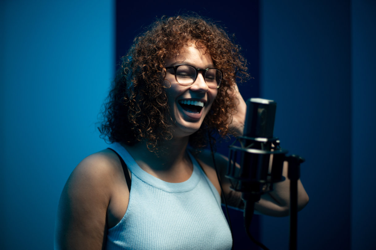 A close-up of a student recording, singing into a mic.