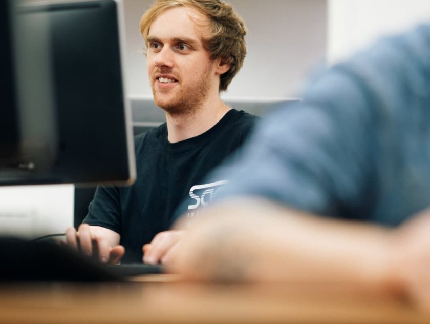 A close up of a student working on a computer.