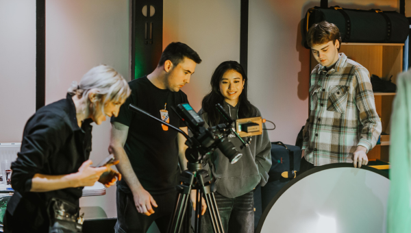 A close up of a group of students working on a filming project.