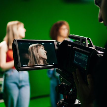 A close up of a film camera filming a pair of students in a film studio.