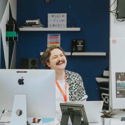 A close-up of a staff member smiling behind a desk.