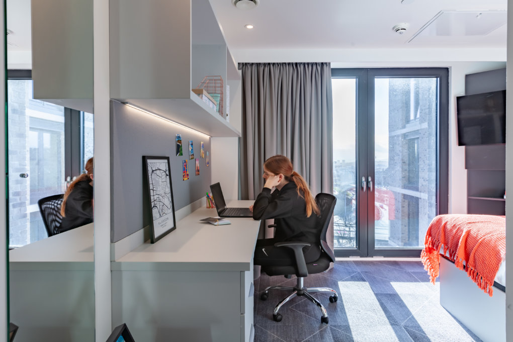 A picture of a student working on their laptop on the desk of their student accommodation.