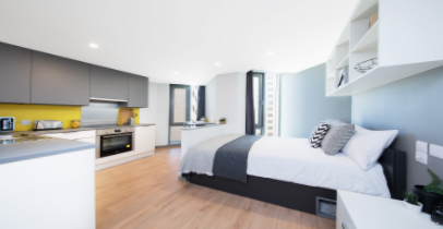 A picture of a student accommodation room in Liverpool, featuring a double bed, a study desk and chair, and fully equipped kitchen.